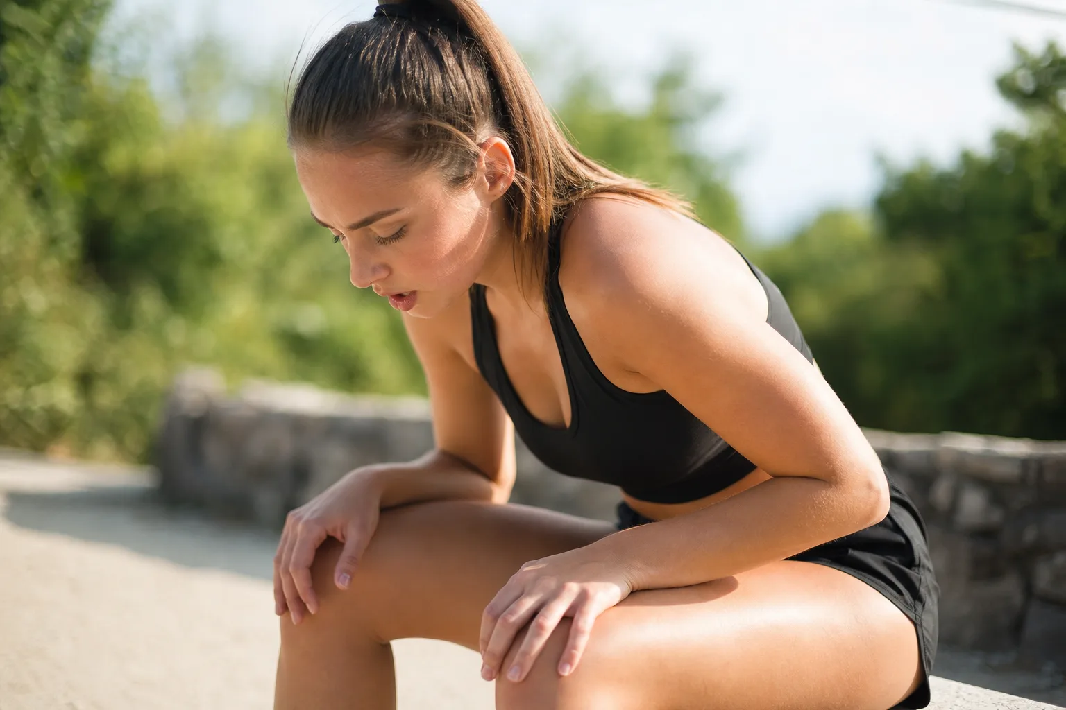 Sportif reprenant son souffle après un effort intense, mains posées sur les genoux