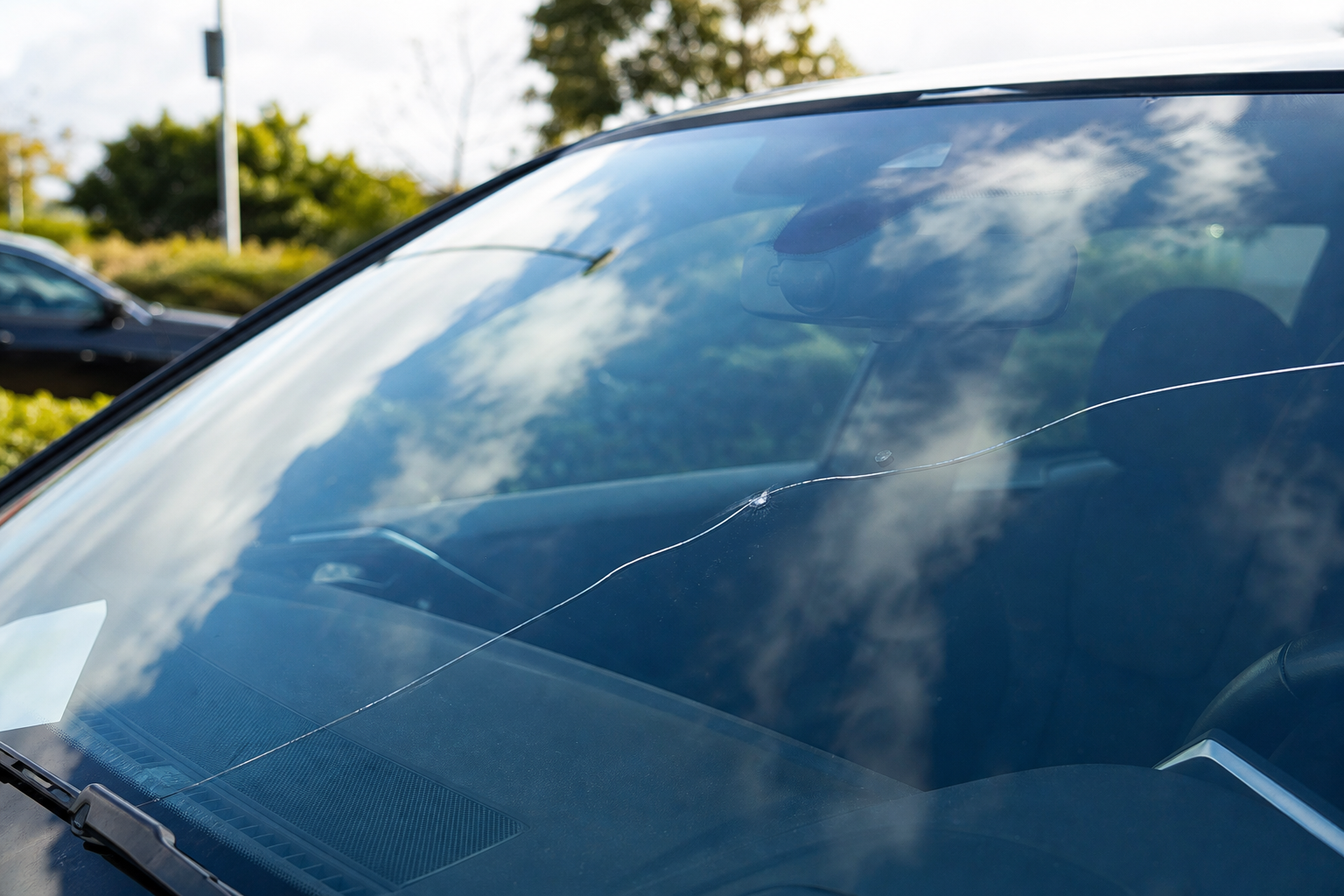 Gros plan sur une fissure fine traversant un pare-brise de voiture, sans impact visible aux alentours