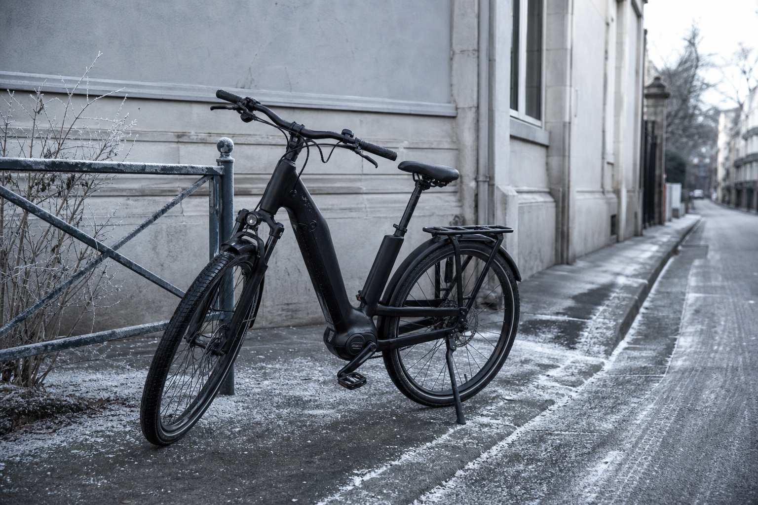 Vélo électrique garé dans une rue en hiver, sacoche de batterie visible sur le cadre